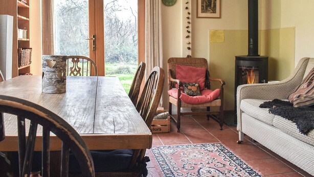 A cozy living room with a fireplace, a dining table, and a sofa.