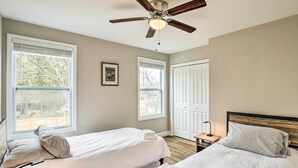 A bedroom with two beds, a ceiling fan, and large windows. - Modern Candler Home w/ Deck & Yard! (Candler)