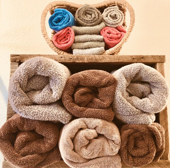 A wooden tray with rolled towels in various colors.