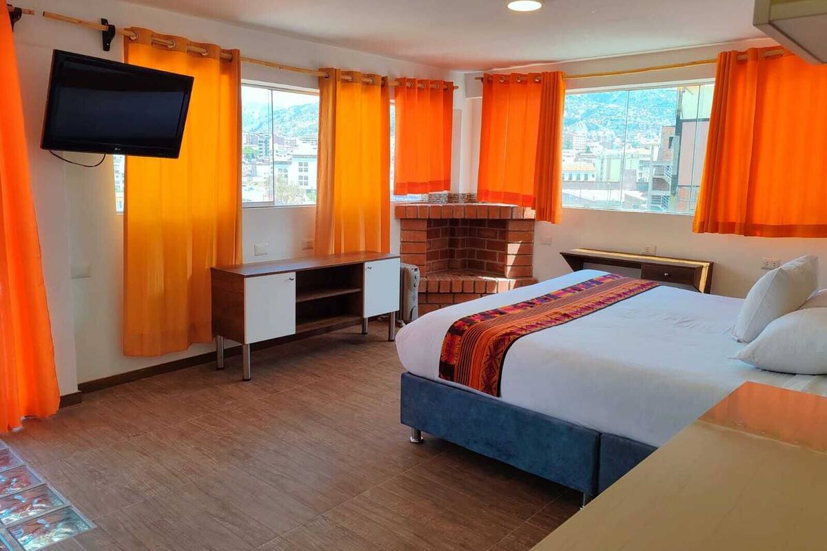 A hotel room with a bed, desk, and fireplace.