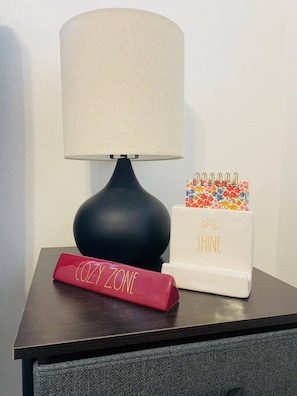 A bedside table with a black lamp, a red sign labeled "COZY ZONE," and a white box with "SHINE" written on it. - Bay Street Unit 3 · Charming & Cozy APT-Free Parking (Appleton)