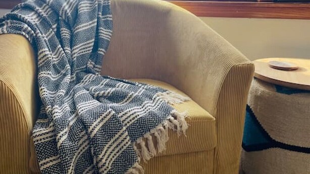A yellow armchair with a blue and white patterned throw blanket. - Bay Street Unit 3 · Charming & Cozy APT-Free Parking (Appleton)