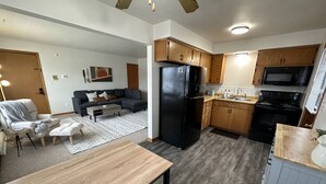 A modern kitchen with wooden cabinets, a black refrigerator, and a microwave. - Chic & Cozy APT-Self Check-In (Appleton)