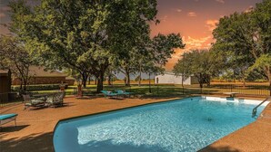 A swimming pool with lounge chairs and tables, surrounded by trees and a fence. - Farmhouse & Ranch style living for your vacay with pond, gazebo, trellis, pool.. (Farmersville)
