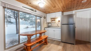 Una cocina con armarios de madera, un refrigerador de acero inoxidable, una mesa de madera y un banco.