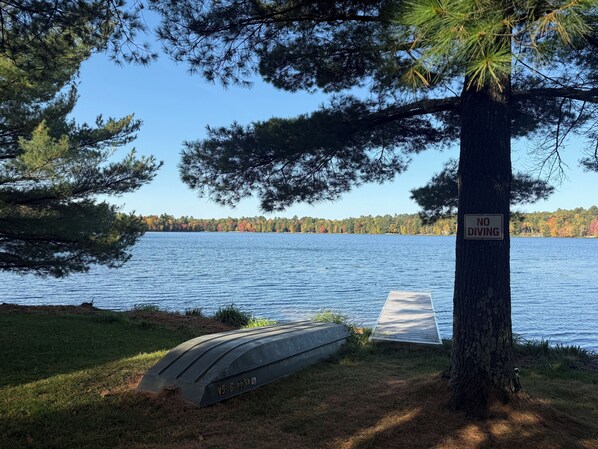 En vy över sjön med en skylt som säger ”Hoppa inte i”, en brygga och ett gräsområde.