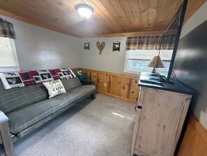 Interior acogedor de una cabaña con un sofá, una mesita y un armario.