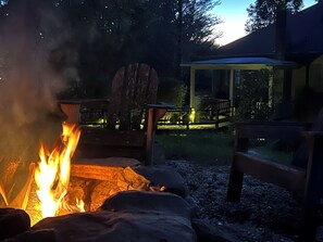 Un feu de camp avec une structure en bois en arrière-plan.