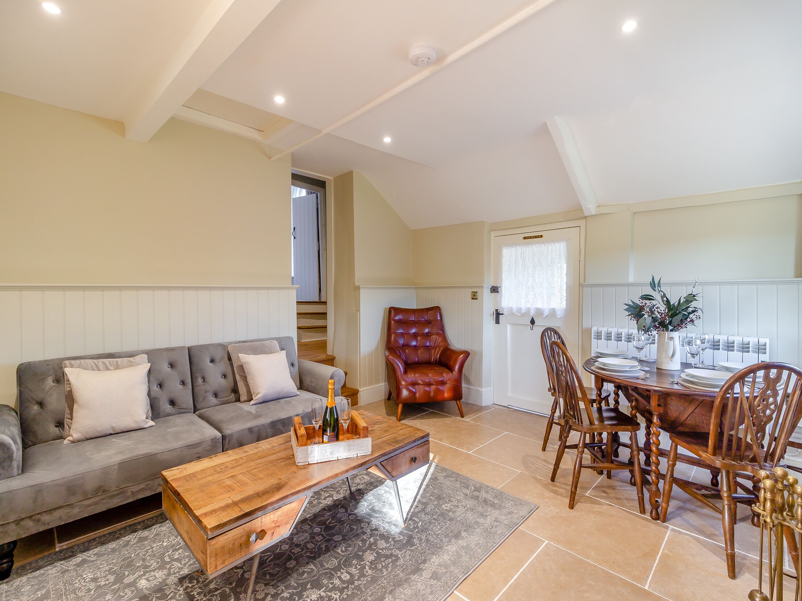 A living room with a sofa, a wooden coffee table, and a dining area with a table set for two.