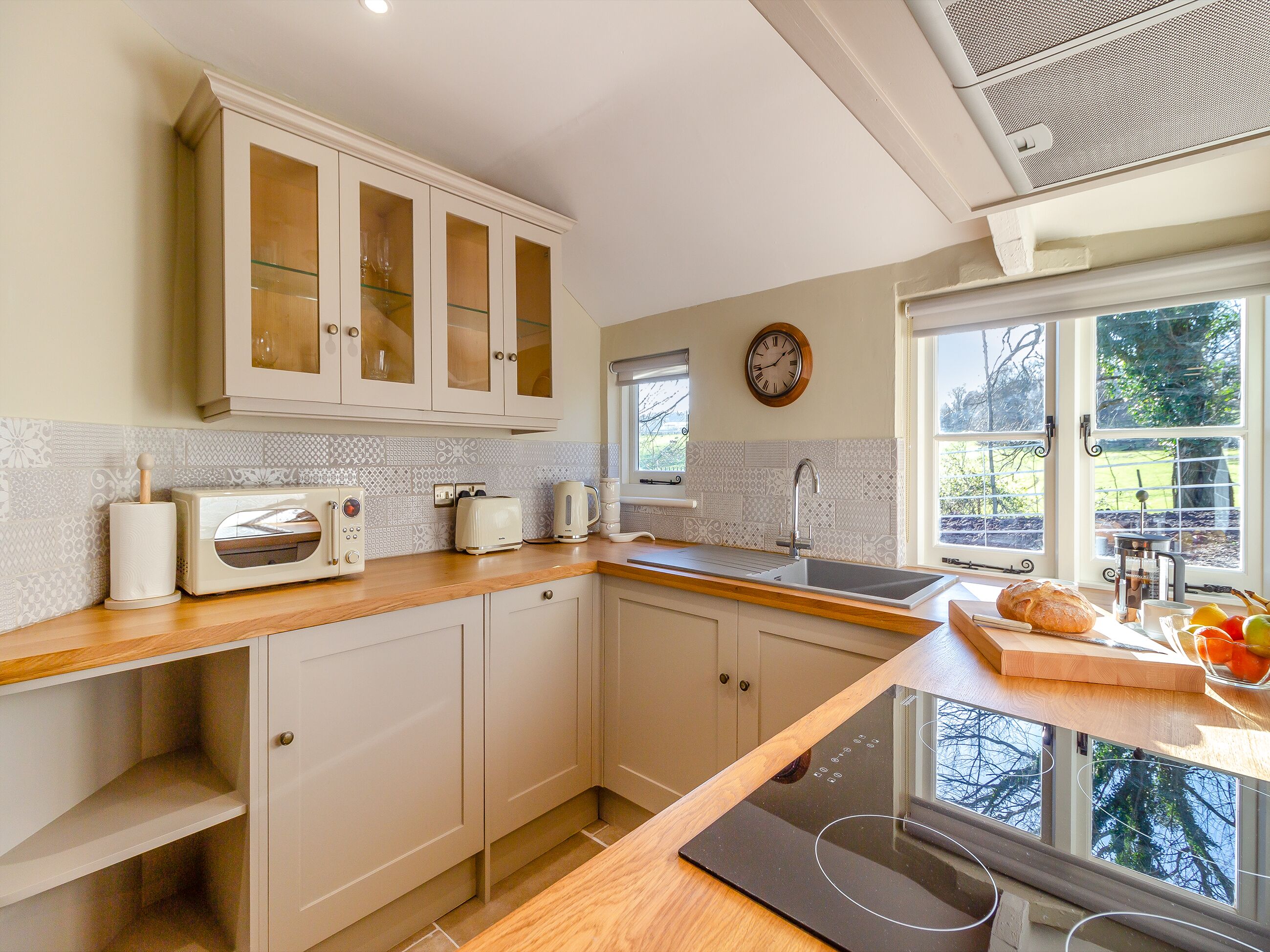 A kitchen with white cabinets, a wooden countertop, a built-in toaster, a coffee maker, and a window with a view of greenery.