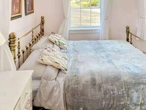 A bedroom with a bed, a dresser, and a window.