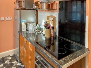 Una cocina con tope de inducción negro, electrodomésticos de acero inoxidable y un armario de madera.