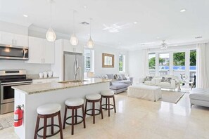 Uma cozinha moderna com ilha central, banquetas e eletrodomésticos de aço inoxidável.