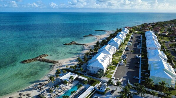 A resort with a long row of white buildings, a beach, and clear blue waters.