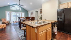 A kitchen with a wooden island, a black refrigerator, and wooden cabinets.