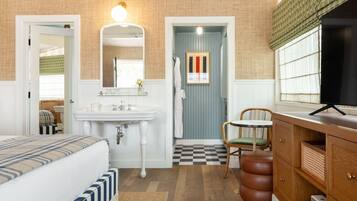 Une chambre à coucher avec un lit, une table de chevet, un miroir, un lavabo et une chaise.