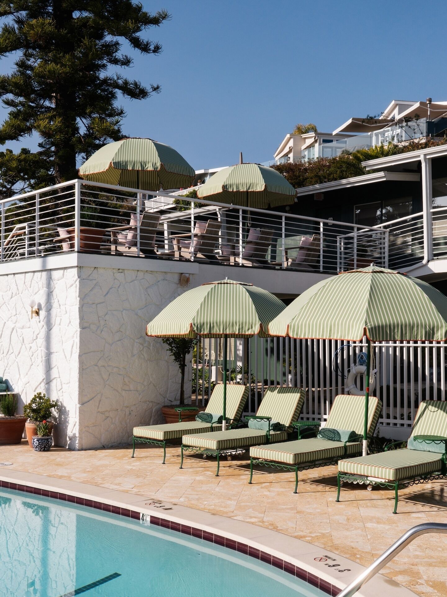 Una piscina al aire libre, sombrillas, sillones reclinables de piscina