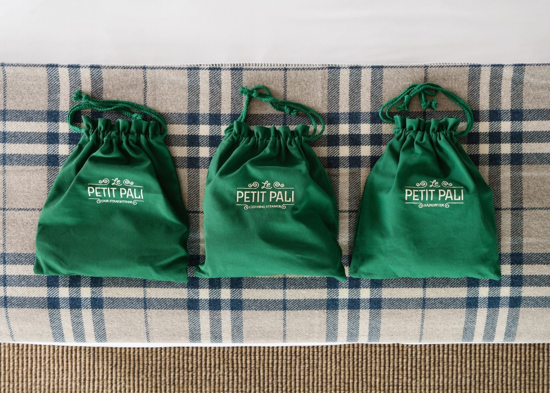 Drie groene zakken met trekkoord, voorzien van de merknaam 'Petit Pali', op een geruit textiel.