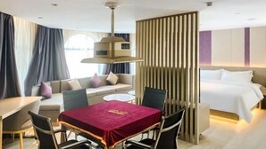 A hotel room with a dining table, a sofa, a bed, and a partition wall. - Lavande Hotels (Dongguan)
