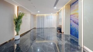 A modern hotel lobby with a marble floor, a potted plant, and a large abstract painting on the wall. - Lavande Hotels (Dongguan)