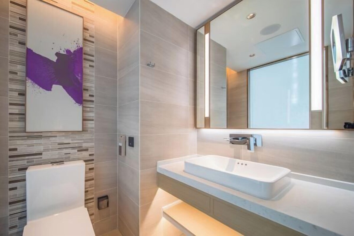 A modern bathroom with a white toilet, a rectangular sink, and a large mirror.