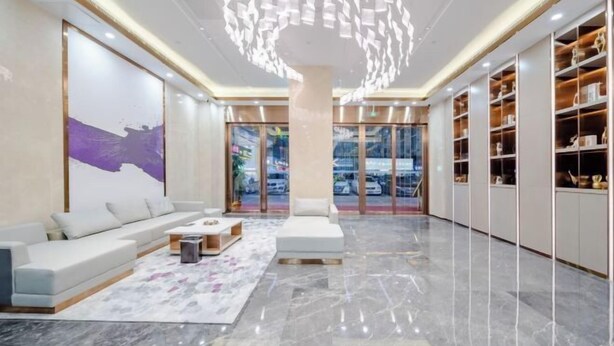 A modern lobby with a marble floor, white sofas, a coffee table, and a large abstract painting. - Lavande Hotels (Dongguan)