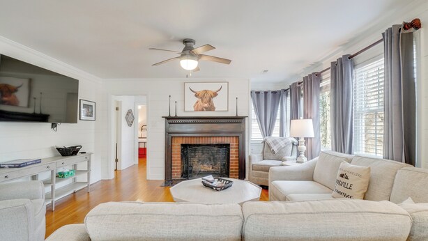 A living room with a fireplace, sofa, television, and a ceiling fan. - Family-Friendly Knoxville Home: Close to UT! (Knoxville)