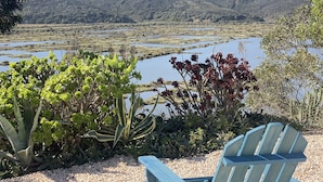 A view of a lake surrounded by hills, with a chair and plants in the foreground. - Jasmin House | Herdade d' Amoreira (Aljezur)