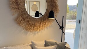 A living room with a round mirror, a floor lamp, and a sofa with cushions. - Jasmin House | Herdade d' Amoreira (Aljezur)