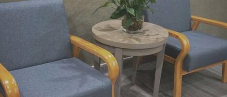 Un rincón de descanso con dos sillones tapizados en azul y una mesa redonda con una planta en maceta.
