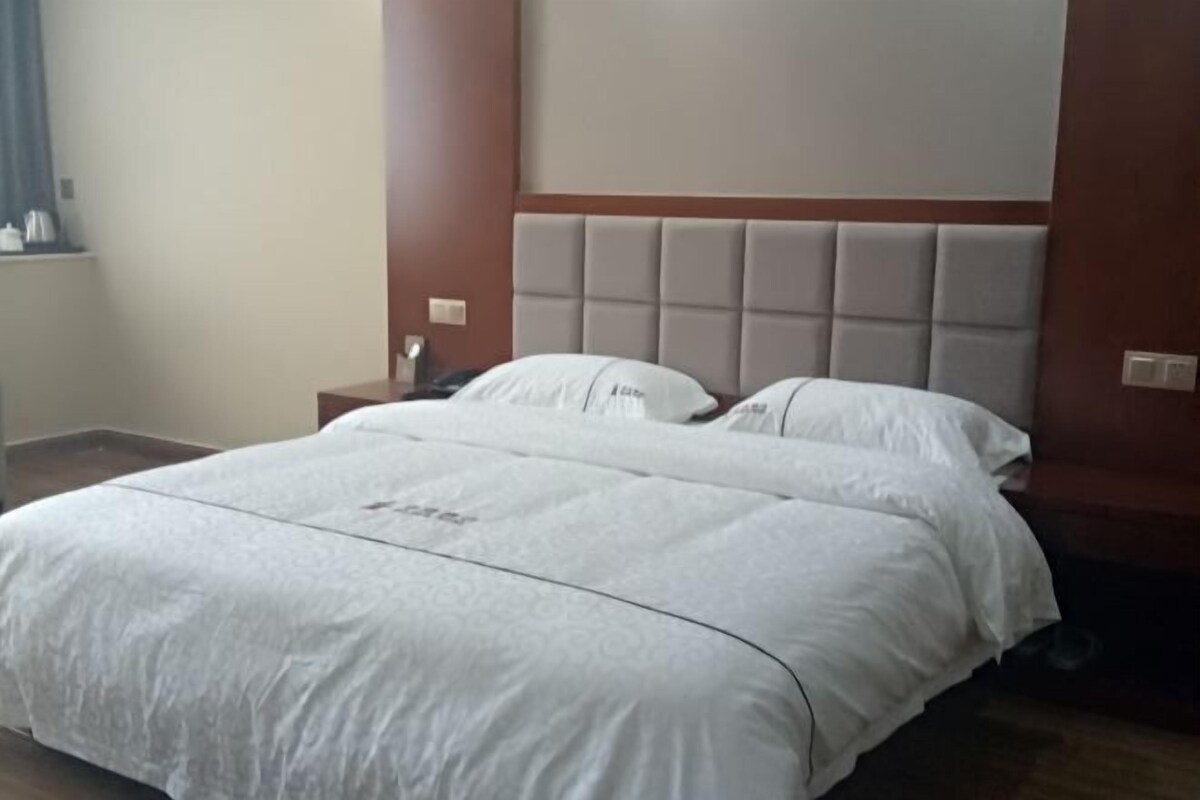 Una habitación de hotel con una cama grande, una mesita de noche y un cabecero.