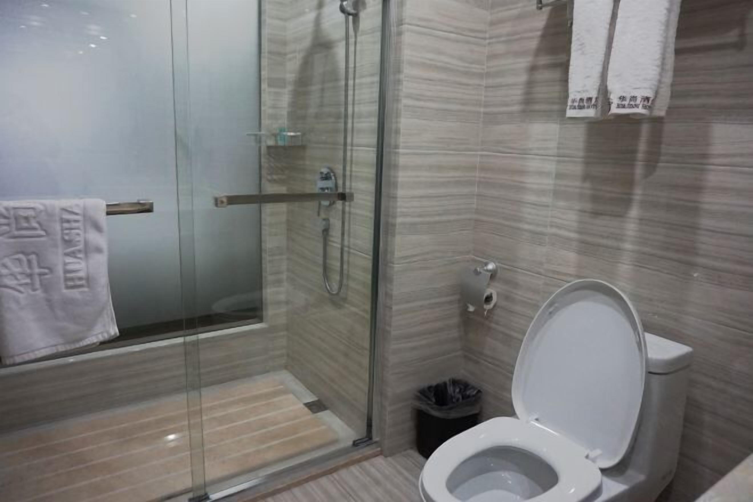 Un baño moderno con ducha acristalada, inodoro y cubo de basura.