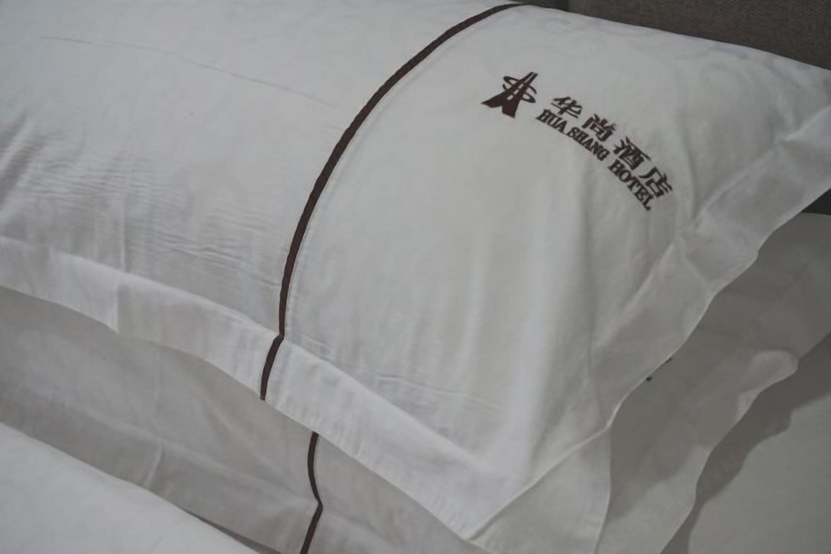 Almohada blanca con un logotipo y texto que indica que pertenece al Hotel Mia Shang.