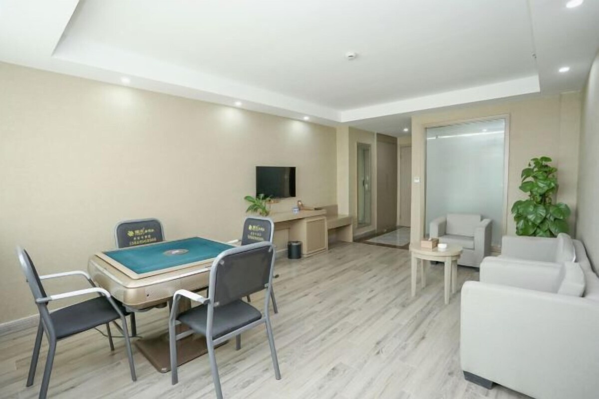 Una habitación con mesa de billar, sofá, televisión y planta en maceta.