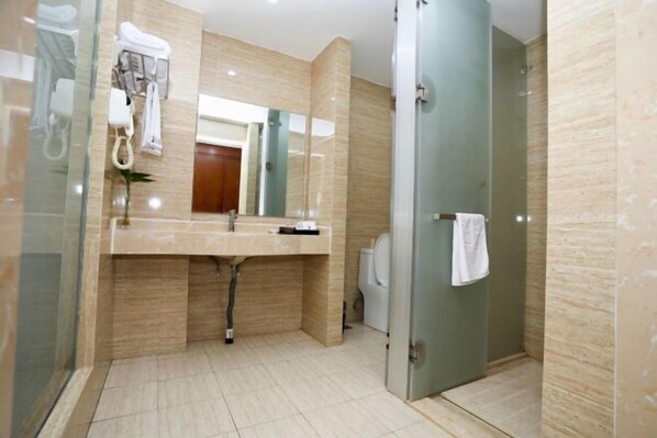 Un baño moderno con cabina de ducha de vidrio, un lavamanos con toallero y un espejo sobre el lavamanos.