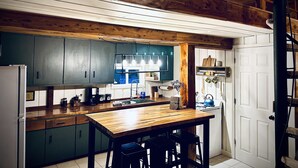 Una cocina con vigas de madera, una mesa de madera y armarios verdes.