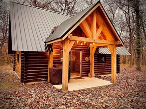 Eine rustikale Holzhütte mit Metalldach, Holzbalken und einer Veranda.
