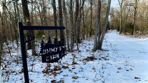 Un poste con el letrero 'Jimmy's Cabin', rodeado por un bosque nevado.