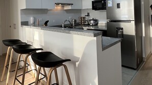 Una cocina moderna con una isla central, electrodomésticos de acero inoxidable y taburetes de bar.