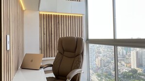 Un espacio de oficina moderno con un amplio ventanal, un escritorio con una computadora portátil y una silla acolchada.