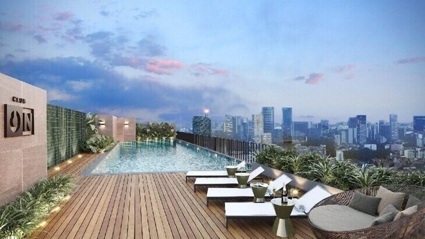 Un área de piscina en la azotea con sillones reclinables y vistas al horizonte de la ciudad.
