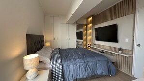 Un dormitorio moderno con una cama grande, televisor integrado y armarios empotrados.