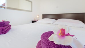Un lit bien fait, avec un oreiller blanc et une serviette violette.
