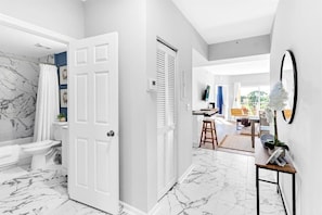 Enjoy a spacious bathroom with a large mirror, potted plant, and convenient access to a living area.