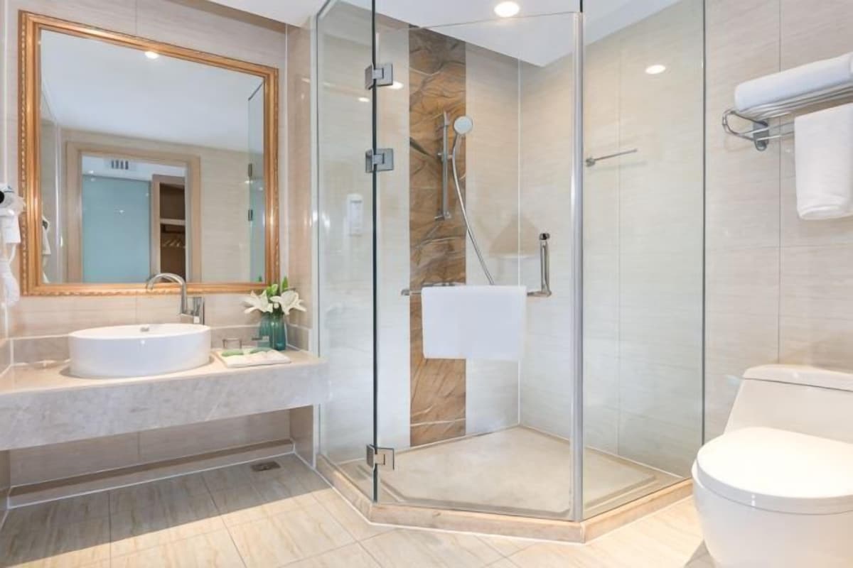 A modern bathroom with a glass-enclosed shower, a sink, and a toilet.