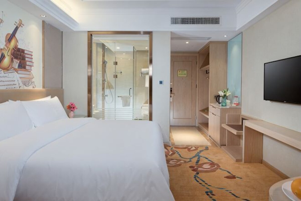 Une chambre d’hôtel avec un grand lit, une télévision, un espace douche et un petit bureau.