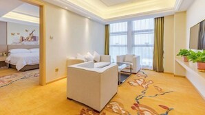 A modern hotel room with a bed, a sofa, a desk, and a large window.
