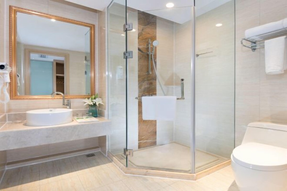 Une salle de bain moderne avec une douche à parois de verre, un lavabo blanc et un grand miroir.