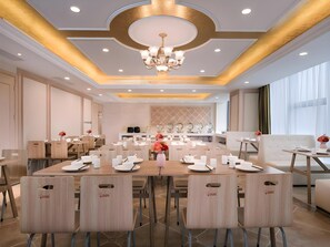 A spacious dining area with a central table set for a meal, surrounded by chairs.