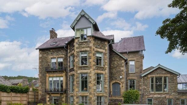 A large stone house with multiple windows and a well-maintained lawn. - Wansfell at Lipwood House (Windermere)